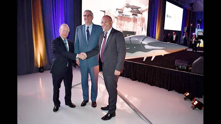Purdue University President Mitch Daniels, Indiana Gov. Eric Holcomb and Saab President and CEO Håkan Buskhe stand in front of a quarter-scale model of the Boeing T-X pilot training program.