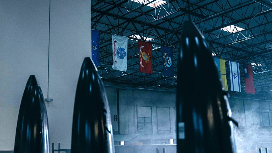Black nose cones foreground and flags hanging from factory ceiling background
