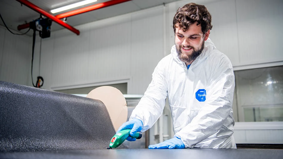 Man standing over sheet of black thermoplastic composite material.