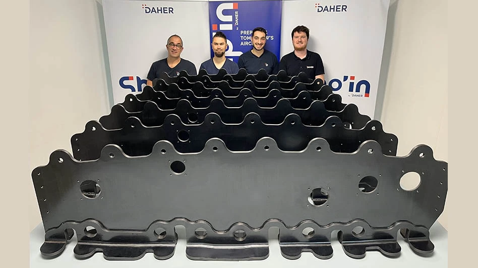 four people stand behind a row of composite wing ribs